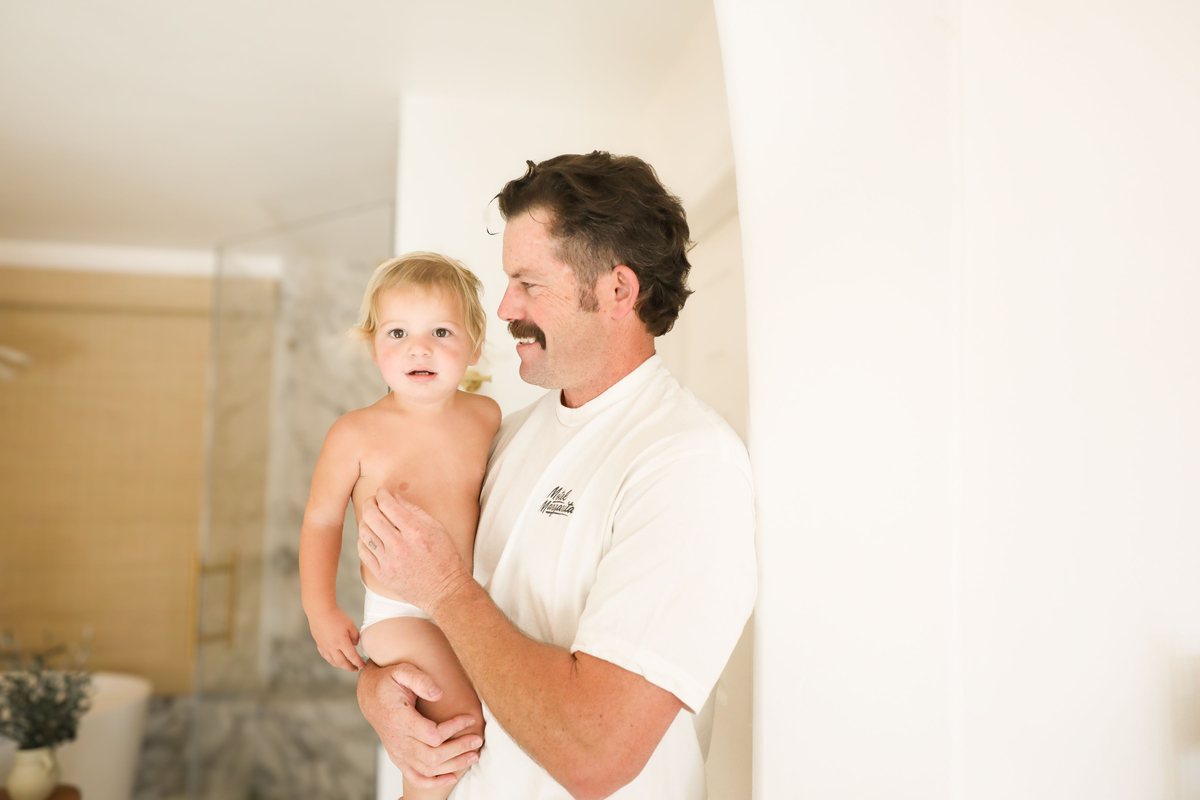 A father holding his smiling toddler at home